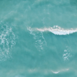 Gentle turquoise waves rolling across the sea Soft turquoise sea waves viewed from above