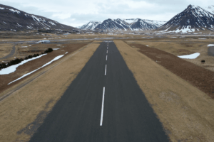 Lonely road stretching through mountain valley Long straight mountain road disappearing into the distance